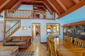Un vaste loft doté d’un escalier en bois, d’un coin repas et d’une cuisine agrémentée d’éléments en pierre.
