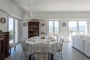Ein Essbereich mit einem runden Tisch, weißen Stühlen und Blick ins Freie.