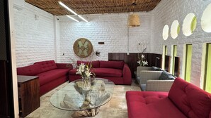 A modern living room with a red sofa, a glass coffee table, and a wooden ceiling. - Hotel Kupuri Sayulita (Sayulita)