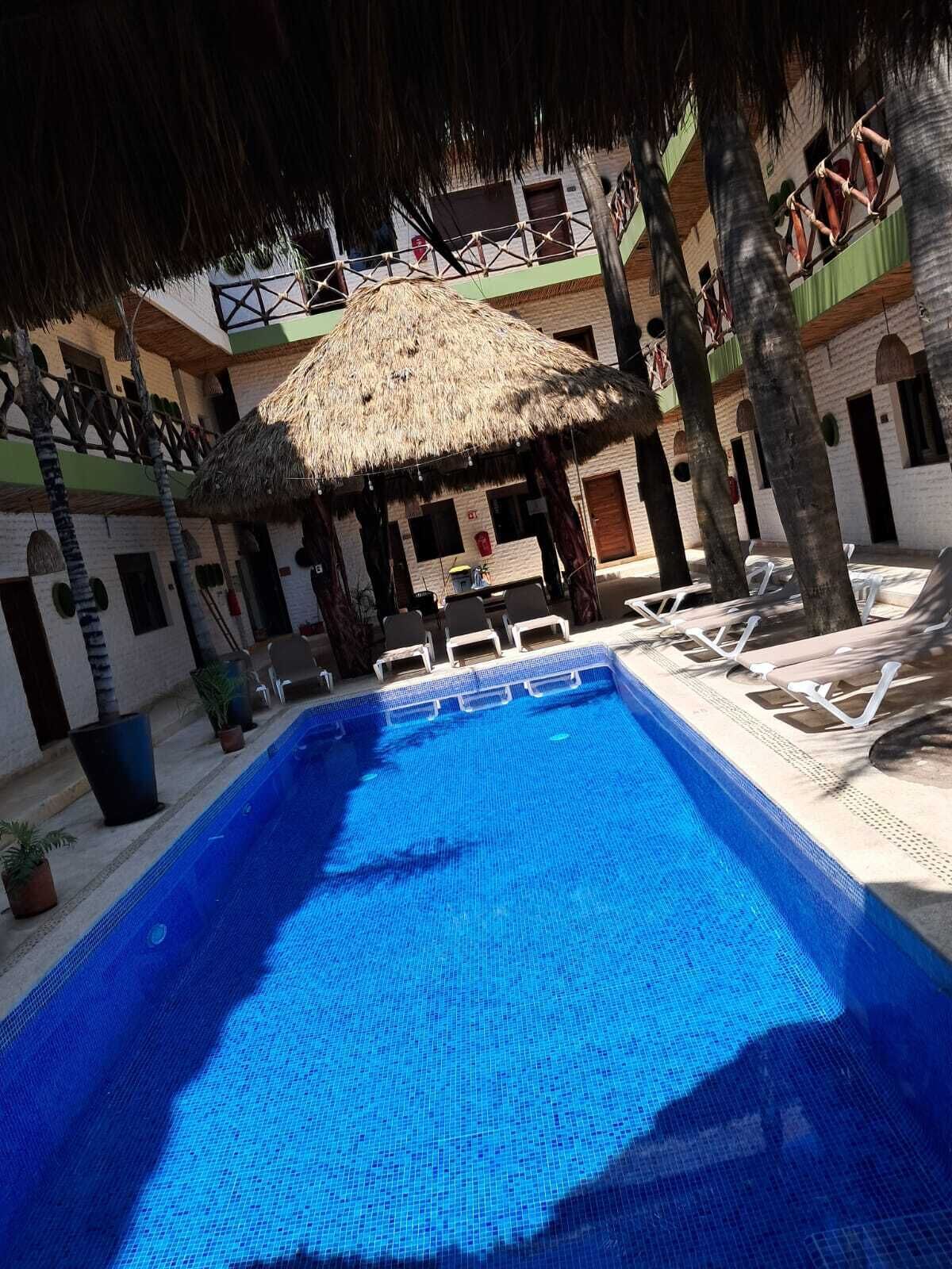 Une piscine avec des chaises longues et un parasol en chaume.