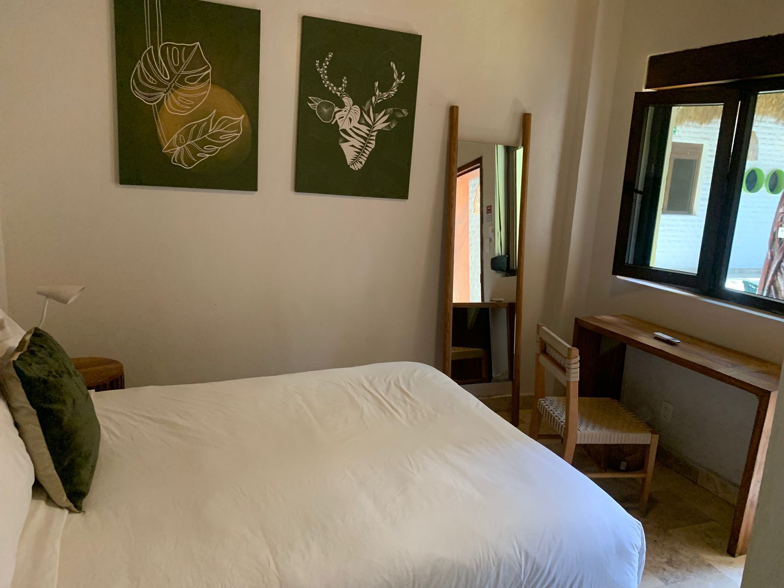 Ein Schlafzimmer mit einem großen Bett, einem Schreibtisch und zwei Wandbildern.