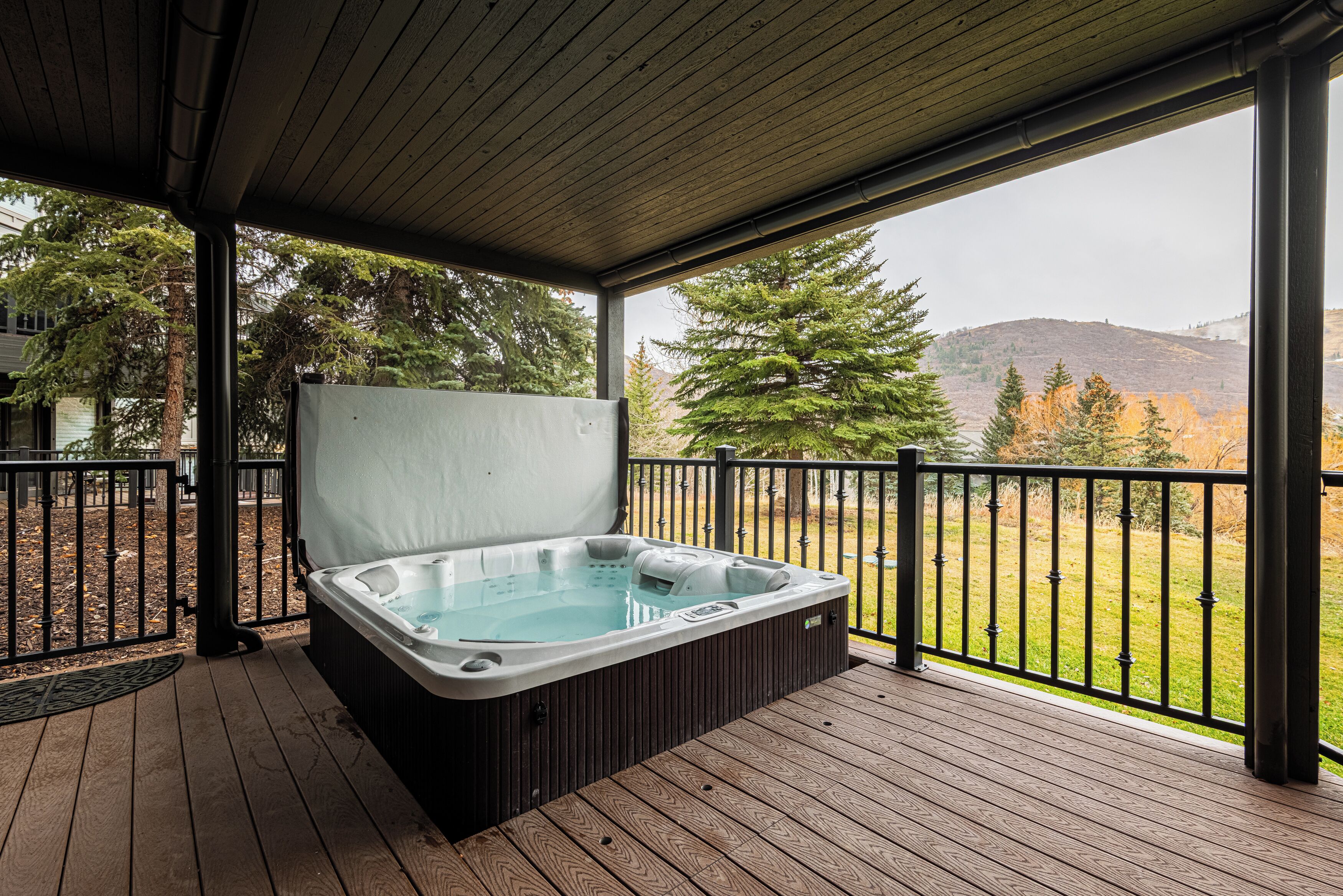 Un bain à remous sur une terrasse en bois, avec vue sur les arbres et les collines.