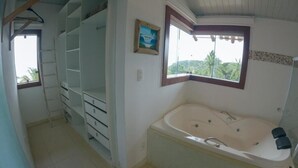 A bathroom with a bathtub, a window with a view, and a shelving unit.
