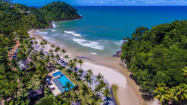 A beach resort with a pool, palm trees, and ocean views.