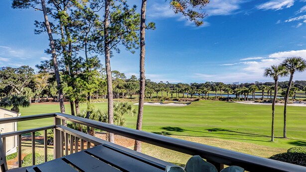 A view from a balcony overlooking a golf course with trees and a clear sky. - Sunset Rentals | Plantation Club 437 | Dog Friendly (Hilton Head Island)