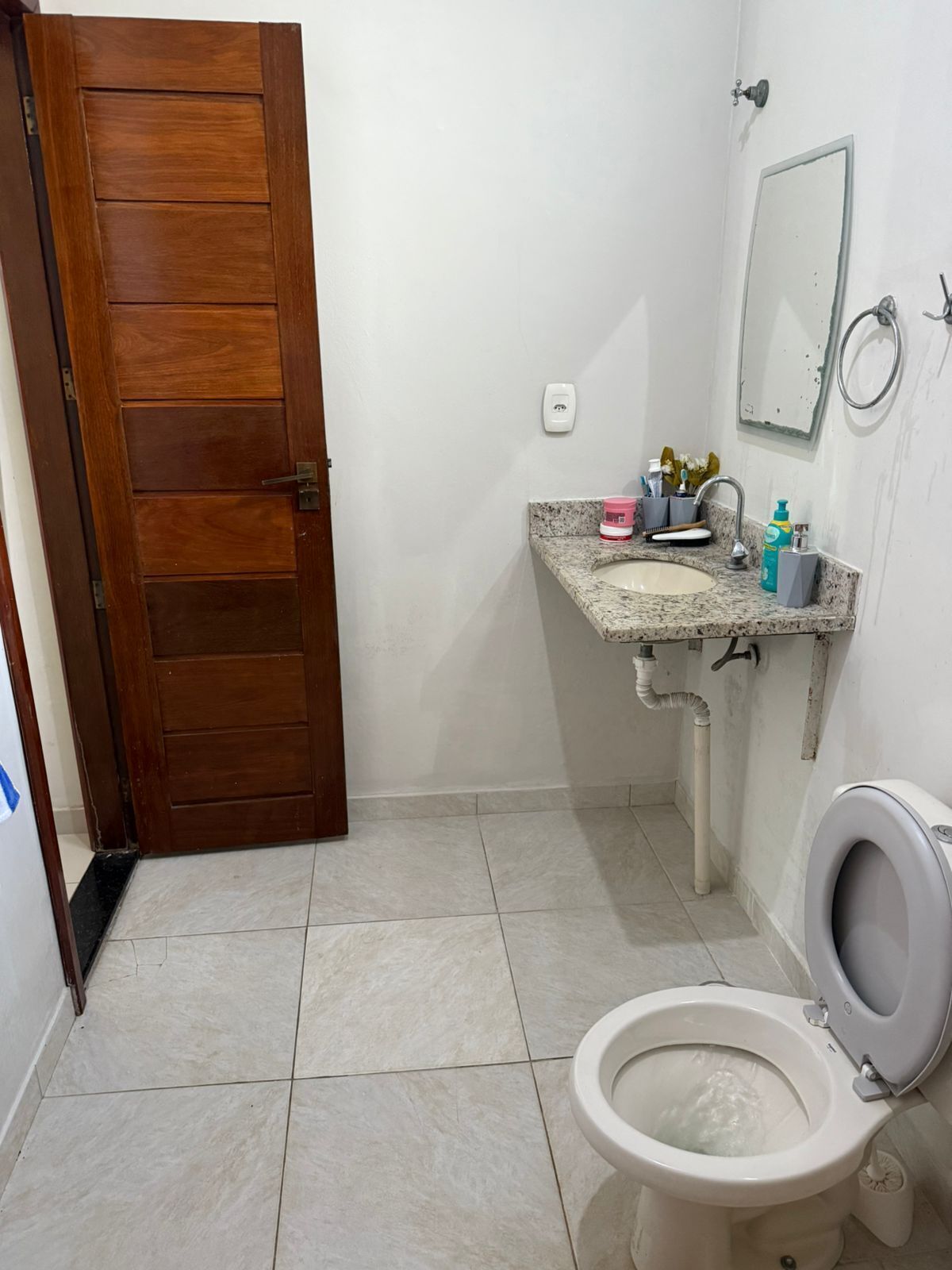 A bathroom with a wooden door, a sink with a mirror, and a toilet.