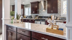 A modern kitchen with dark wood cabinets, a marble countertop, and stainless steel appliances. - Mediterranean Charm Nr Beach/Shopping/EZ Parking (San Francisco)