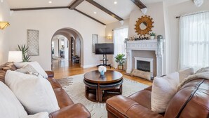 A spacious living room with a fireplace, leather sofas, and a television. - Mediterranean Charm Nr Beach/Shopping/EZ Parking (San Francisco)