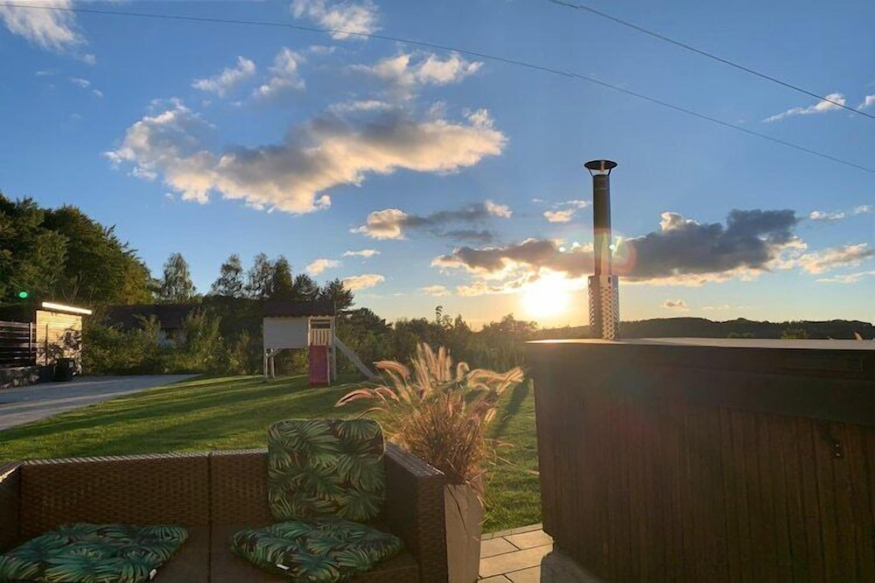 Un jardin avec une pelouse, une clôture en bois et une haute cheminée.