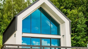 Un bâtiment moderne doté d’un toit triangulaire et de grandes fenêtres qui reflètent le ciel.