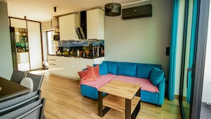 Un salon moderne avec un canapé bleu, une table basse en bois et un coin repas comprenant une table et des chaises.