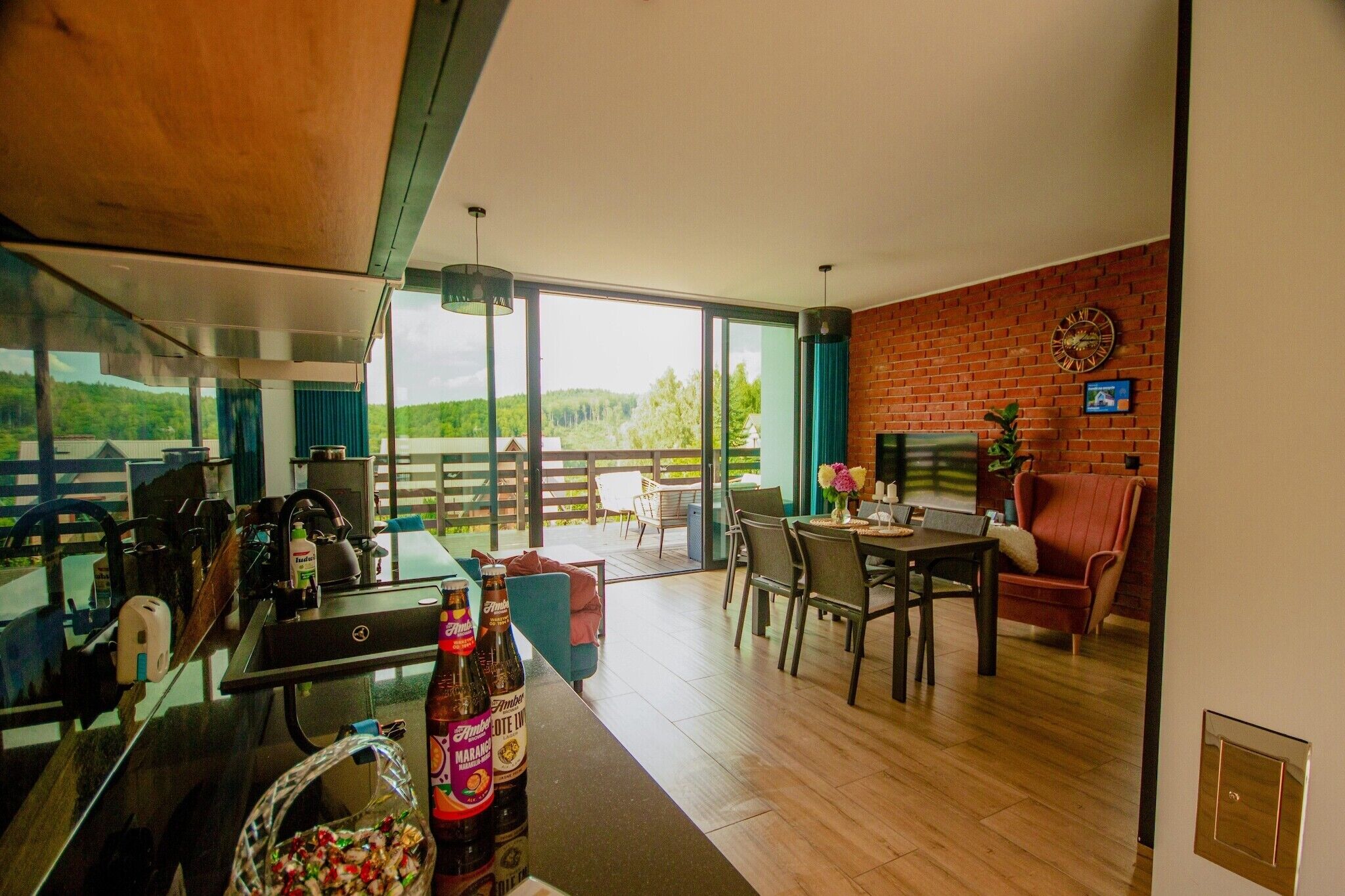 A modern kitchen with a large window, a dining area with a brick wall, and a view of the outdoors.