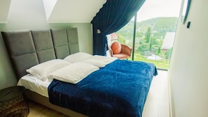 Un dormitorio con cama, una silla, un ventanal y vistas al exterior.
