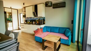 Una sala de estar moderna con un sofá azul, una mesa de centro de madera y un comedor con una mesa y sillas.
