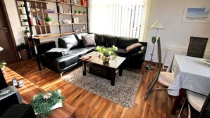 Ein modernes Wohnzimmer mit Ledersofa, Couchtisch und Bücherregal.