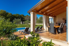 Un espace extérieur abrité comprenant une piscine, des chaises longues et une table à manger.