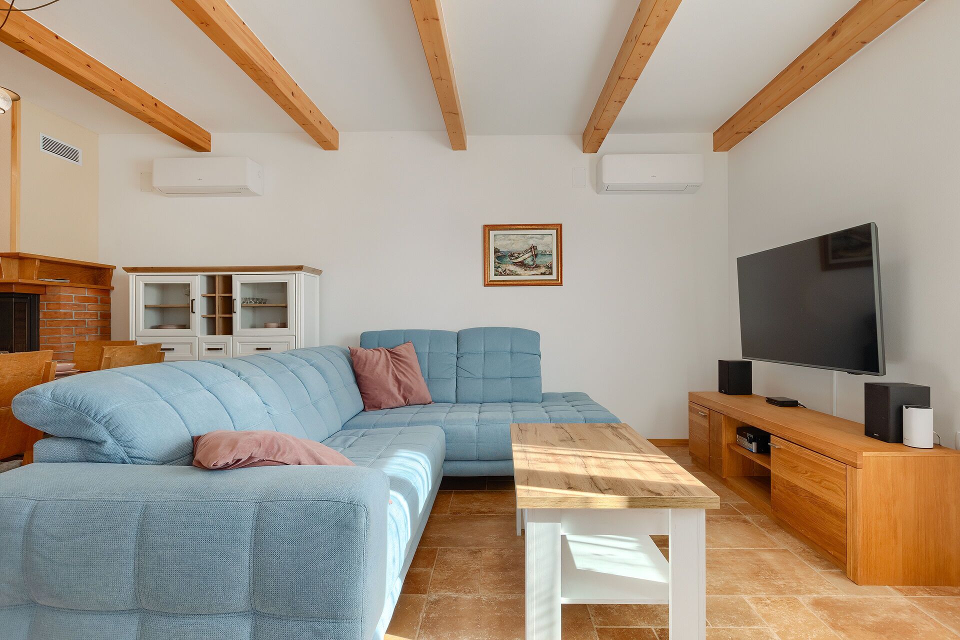 Ein Wohnzimmer mit einem Ecksofa, einem Holztisch, einem Fernseher und einem Schrank.