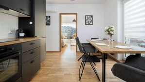 Une cuisine moderne avec des meubles noirs, un plan de travail en bois et un four encastré. On y trouve également un coin repas avec une table en bois, des chaises noires et un vase rempli de fleurs.