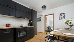 Une cuisine moderne avec des meubles de couleur noire, un plan de travail en bois et un coin repas comprenant une table et des chaises en bois.