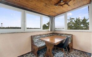 A room with a wooden ceiling, a bench with a table, and large windows offering a view of trees and a water tower. - Apartments Erla (16014-A2) - Banjole (Banjole)