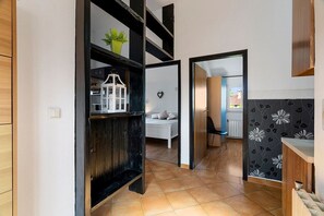 A modern kitchen with a black shelving unit, a white cabinet, and a patterned backsplash. - Apartments Erla (16014-A2) - Banjole (Banjole)