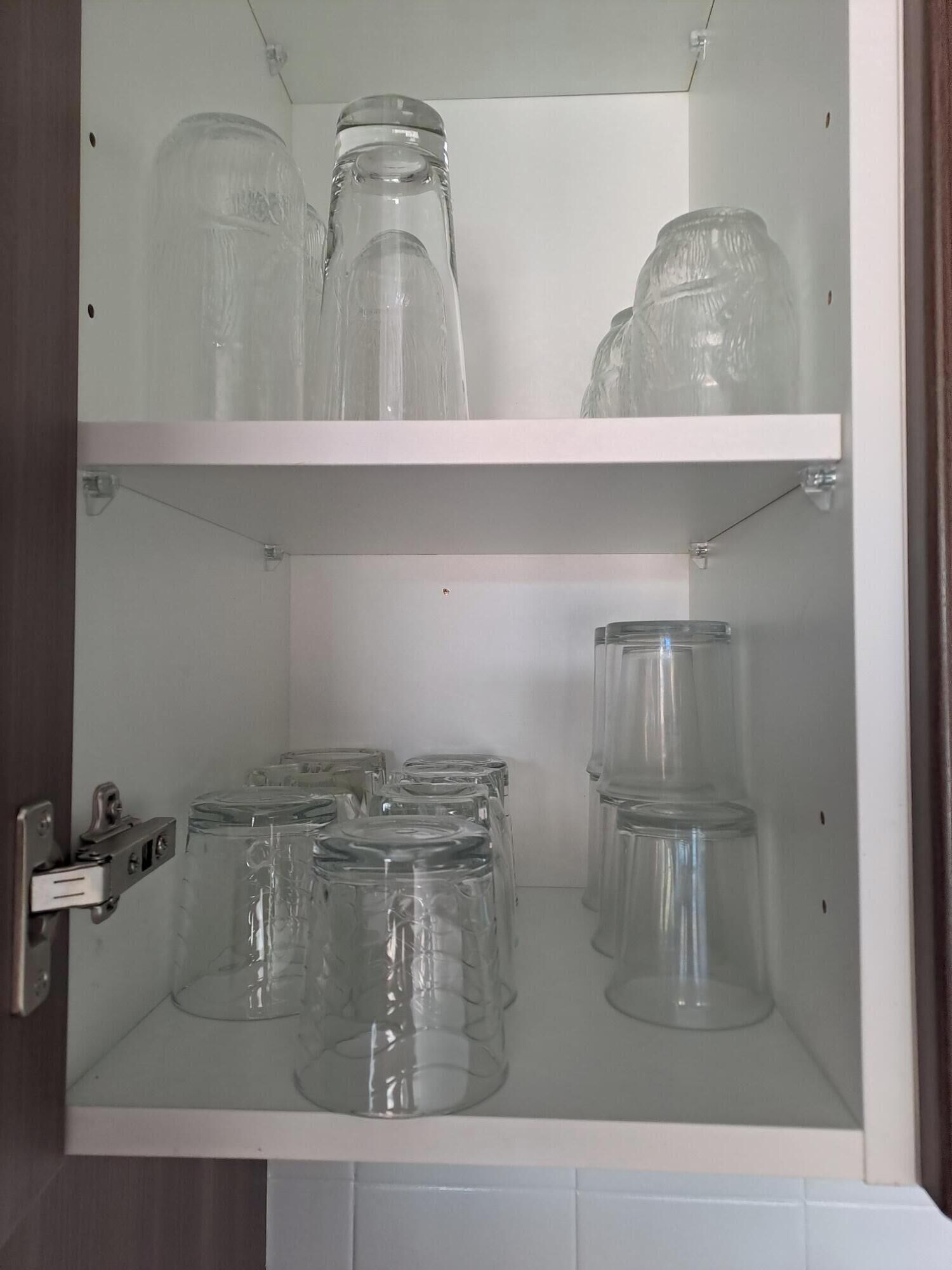 Un mueble con dos estantes, cada uno con frascos y botellas de vidrio transparente.