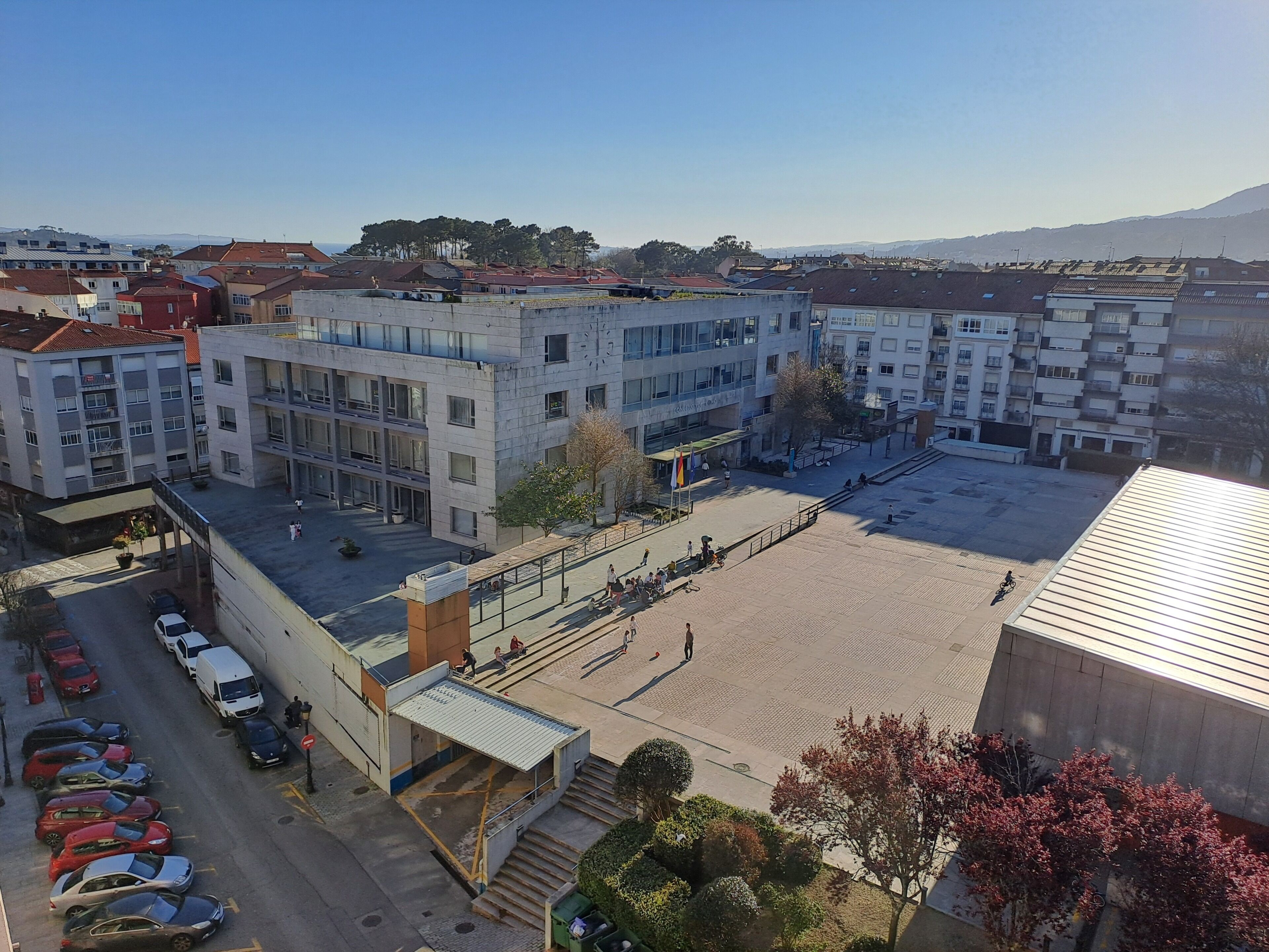 Un edificio de varios pisos con patio, estacionamiento y vista del barrio circundante.