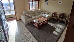 A living room with a sofa, two wicker chairs, a coffee table, and a balcony with a view. - Torre Plaza 4. A cozy apartment in Boiro, beaches and terraces. (boiro)