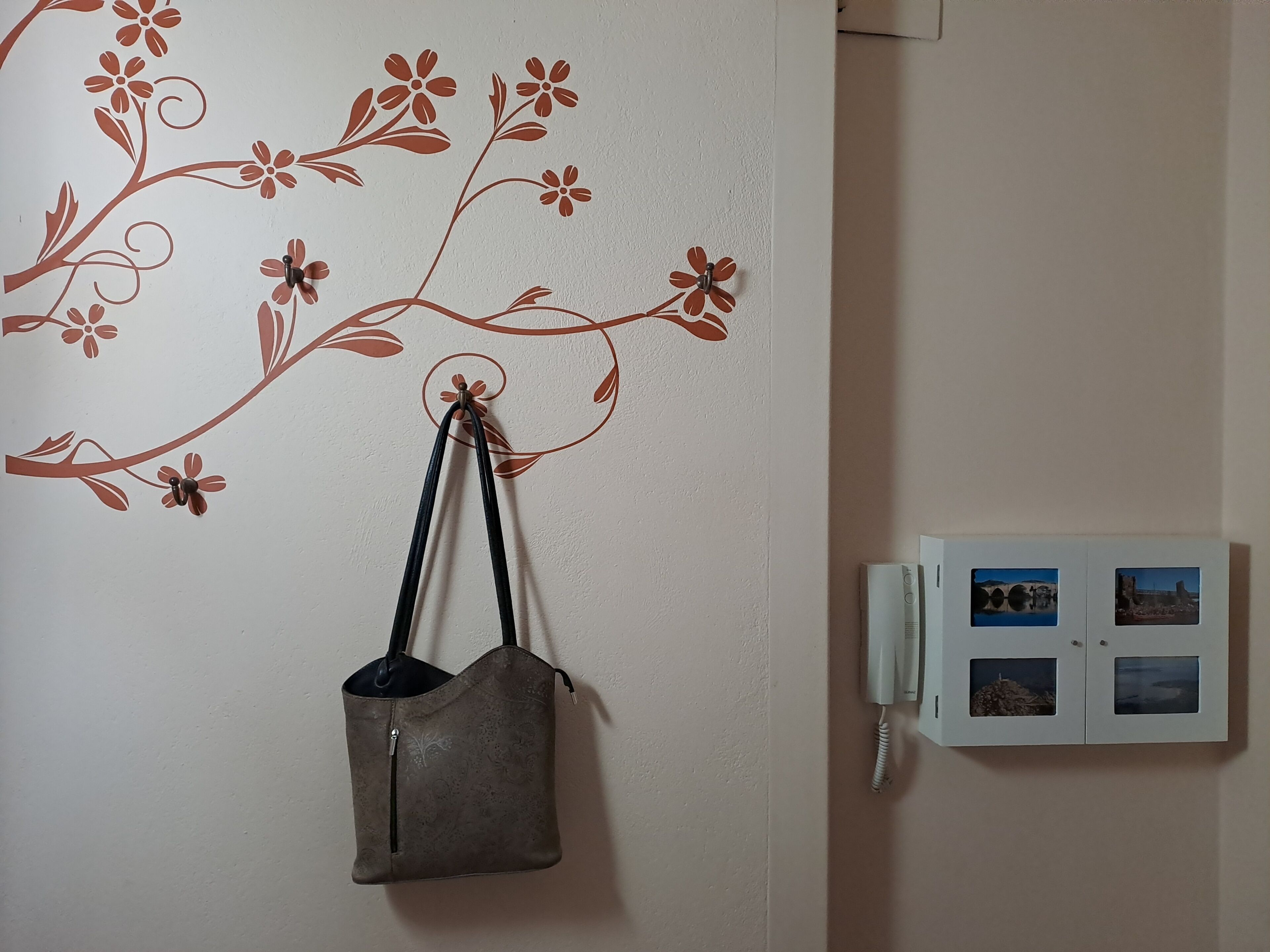 Una pared con un adhesivo floral y un bolso colgante.