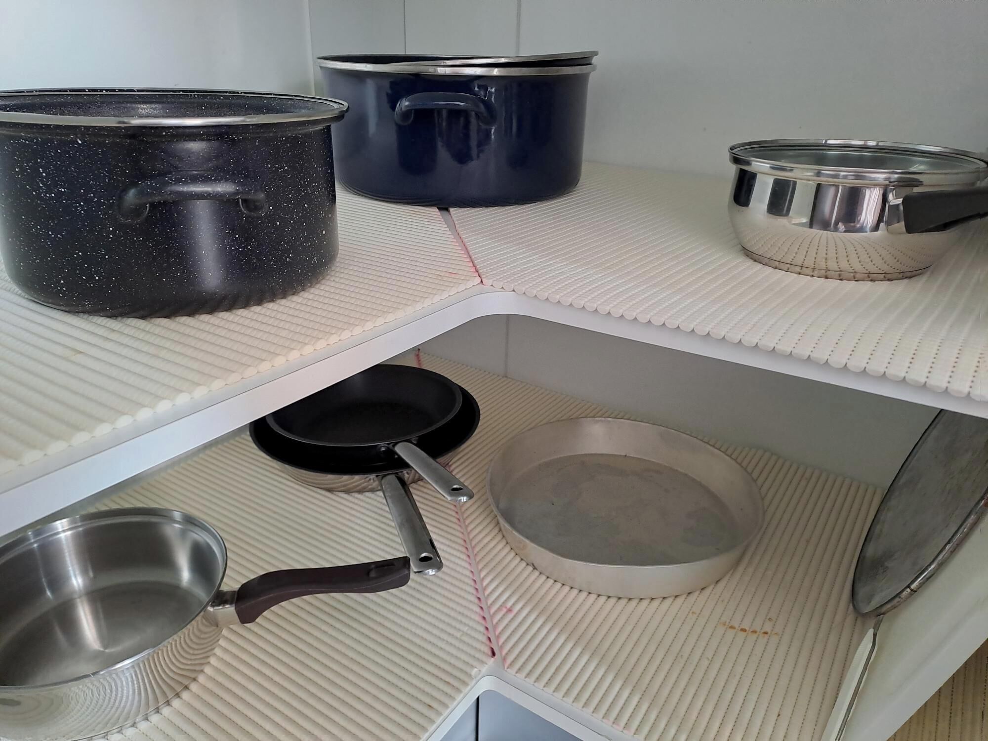 Une cuisine avec trois casseroles sur un égouttoir, une poêle et un petit bol posé sur le comptoir.