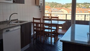 A modern kitchen with a built-in microwave, a dishwasher, and a dining area with a table and chairs. - Torre Plaza 4. A cozy apartment in Boiro, beaches and terraces. (boiro)