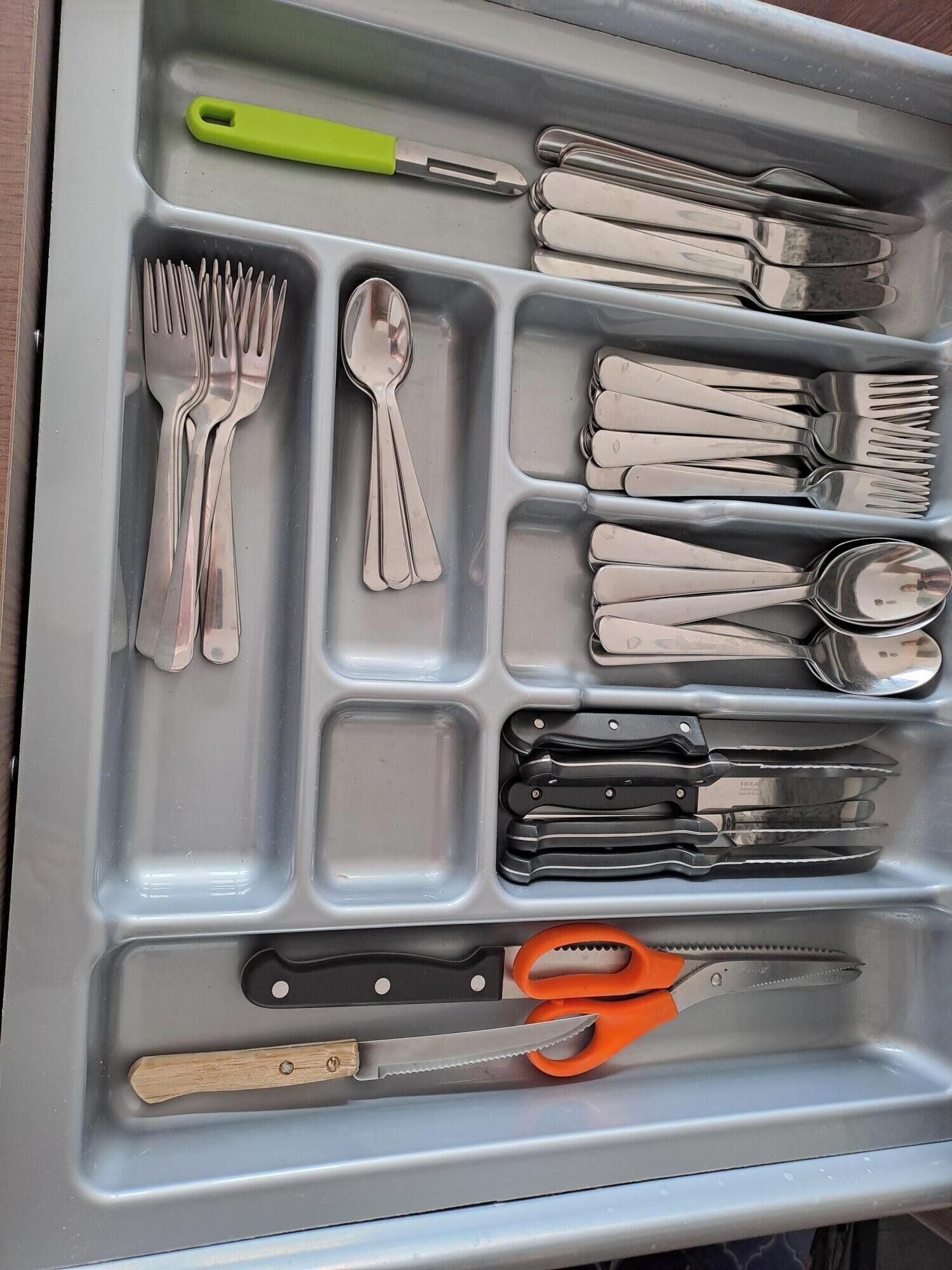 A drawer with utensils, including forks, spoons, and knives, organized in compartments.