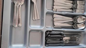 Un cajón con cubiertos, incluyendo tenedores, cucharas y cuchillos, organizados en compartimentos.