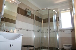 Ein Badezimmer mit Duschkabine aus Glas, Waschbecken in Weiß und Toilette.