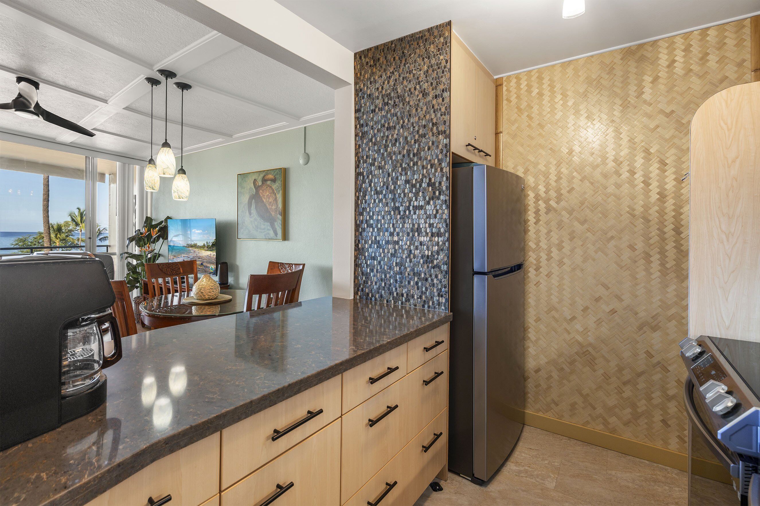 A modern kitchen with a large island, built-in appliances, and a view of the ocean.