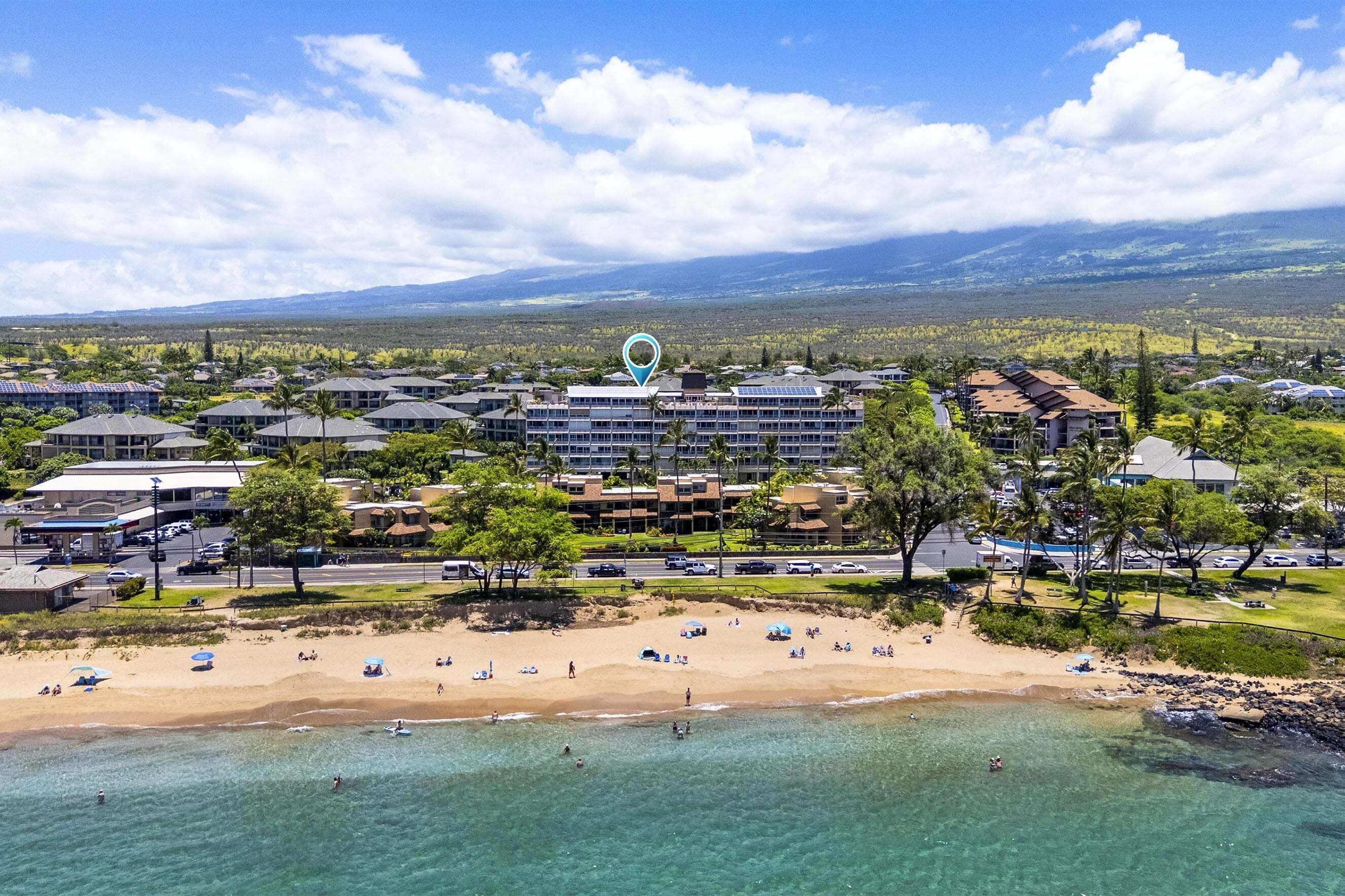 A coastal hotel with multiple buildings, a beach, and clear blue waters.