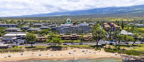 A coastal hotel with multiple buildings, a beach, and clear blue waters.