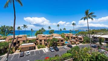 A hotel with multiple buildings, a parking lot, and a view of the ocean.