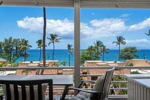 A balcony with a view of the ocean, palm trees, and buildings. - Kamaole Beach Royale (Kihei)