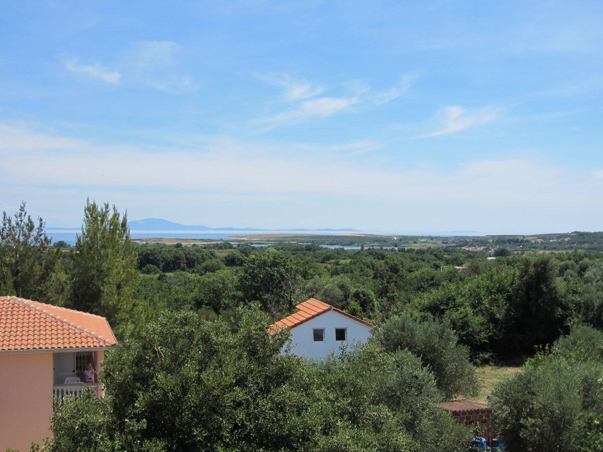 Une maison entourée d’une végétation luxuriante, offrant une vue dégagée sur la mer et les montagnes lointaines.