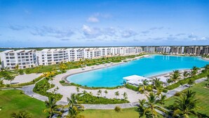 Un resort con una grande piscina centrale, diversi edifici dell'hotel e prati curati.