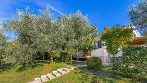 A garden with a stone pathway leading to a building with a white facade and dark shutters. - House Anka (16038-K1) - Medulin (Medulin)