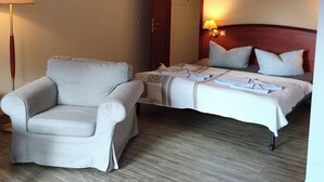 A hotel room with a single bed, a chair, a wooden floor, and a door. - Pension Hafenblick - Rooms with city view (Barth)