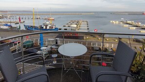 A terrace with two chairs and a table overlooking a marina with boats and a pier. - Pension Hafenblick - Zimmer mit Balkon Hafenblick (Barth)