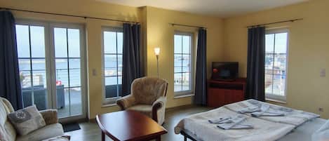 Une chambre d’hôtel avec un lit, un canapé, une chaise, un bureau et une télévision.