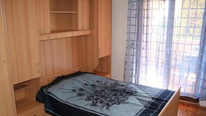 Une chambre à coucher avec un lit, une armoire en bois et une fenêtre avec des rideaux.