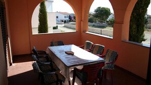 Un espace repas comprenant une table et des chaises, de grandes fenêtres en arc de cercle et une vue sur la rue.