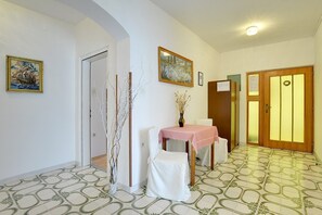 A hallway with a tiled floor, a white chair, a table with a pink tablecloth, and a door with a wooden frame. - Apartments Danilo (16068-A1) - Medulin (Medulin)