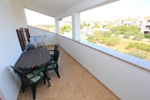 Varanda com mesa e cadeiras, um varal e vista para uma área residencial.