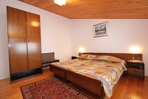 Quarto com cama de madeira, guarda-roupa espaçoso, mesa de cabeceira e tapete.